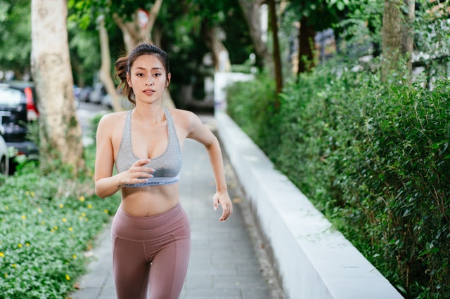 Žena v športovom oblečení beží po ulici